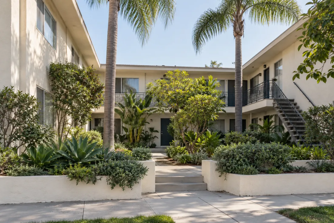 Representative neighborhood scene: A courtyard apartment building with shaded planting and exterior stairs