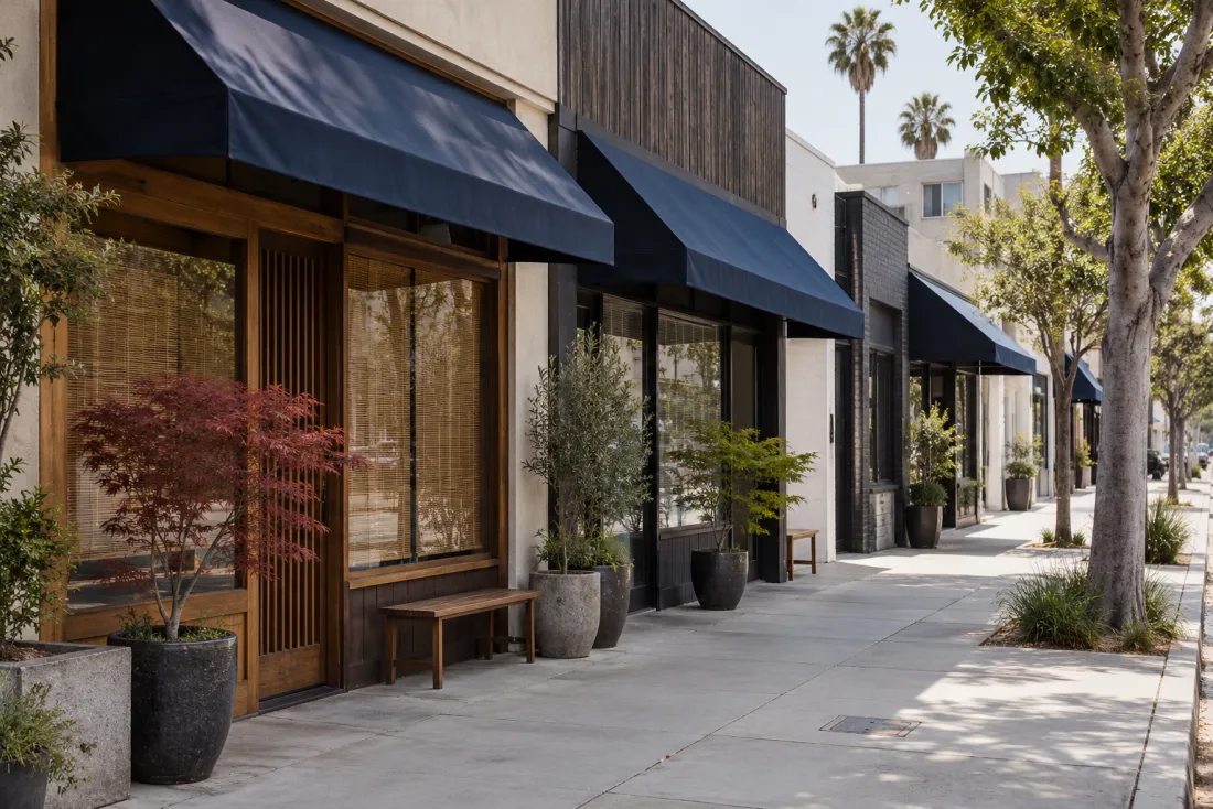 Representative neighborhood scene: Small neighborhood shopfronts with navy awnings and potted maples