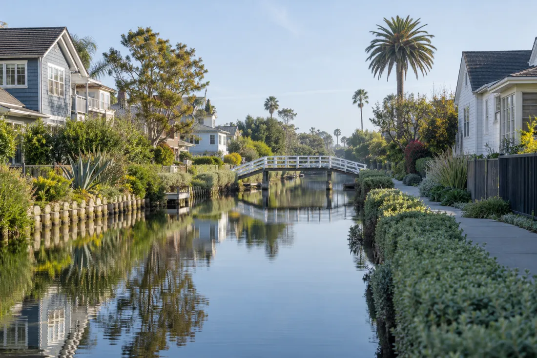 Representative neighborhood scene: A quiet residential canal with a footbridge and waterside homes