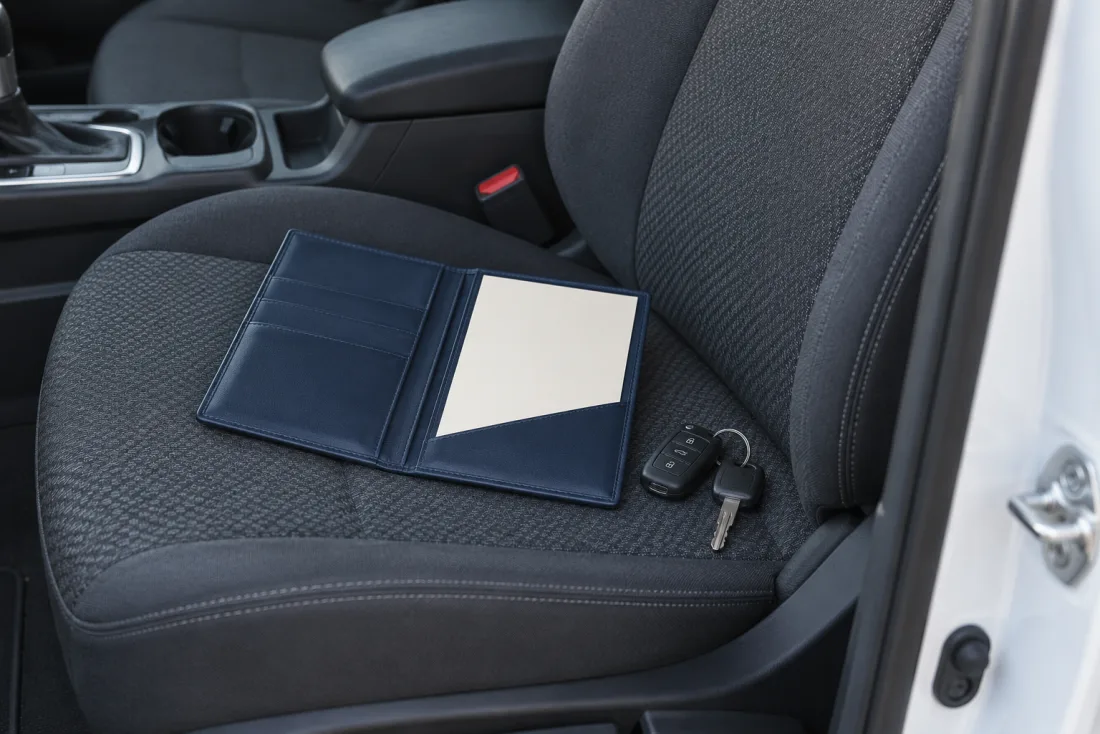 A vehicle document wallet and keys on a passenger seat